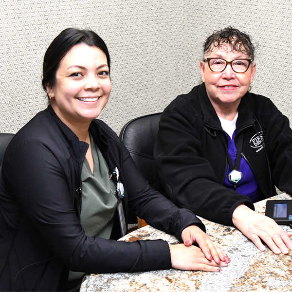 Two staff seated and smiling