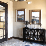 Professional office entryway with black French door, console table, framed mirrors, and neutral decor
